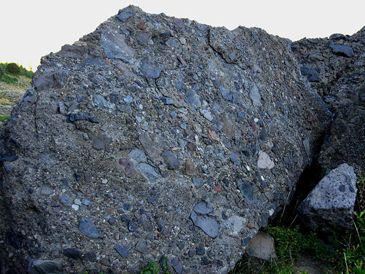 Massive composite boulders holding many types of unaltered stones in a weak cement-type material